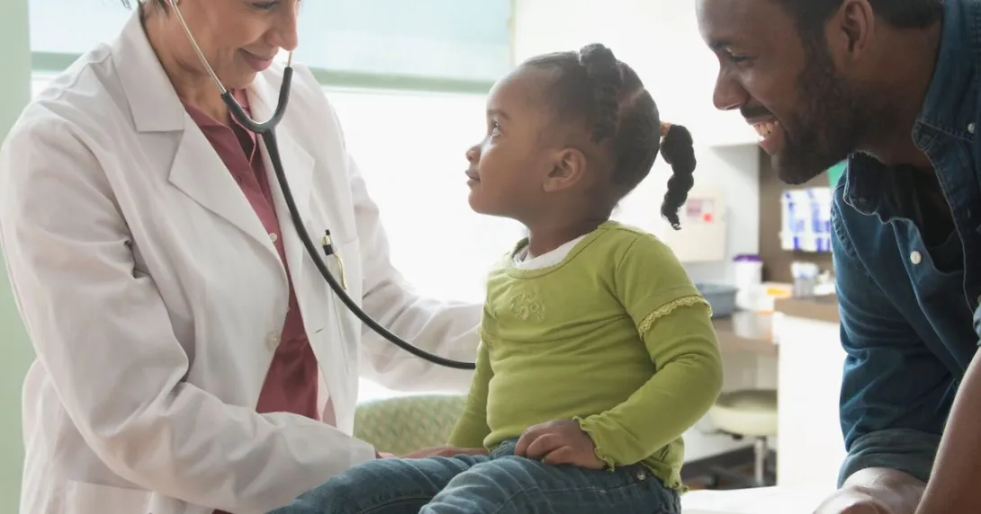 Healthcare provider examining a patient while their caregiver stands nearby watching