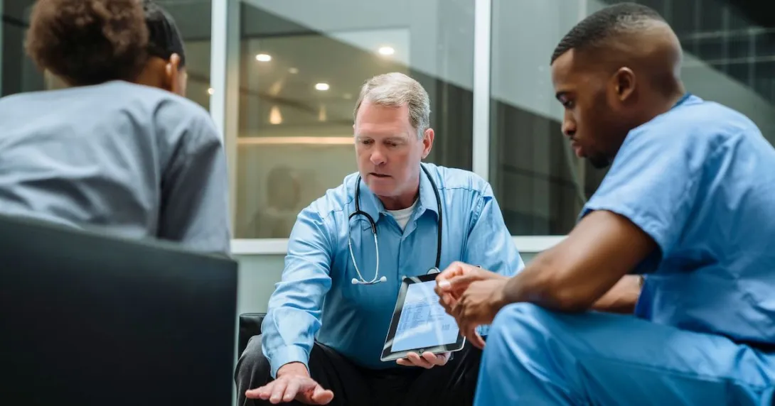 Three healthcare providers sitting around a table looking at a tablet