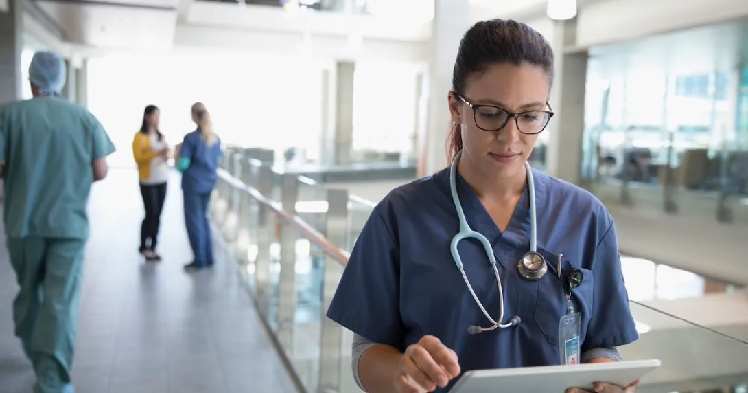 Healthcare provider looking at a tablet in the hallway of a large building