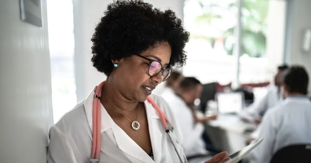 Healthcare provider standing in a hallway looking at a tablet