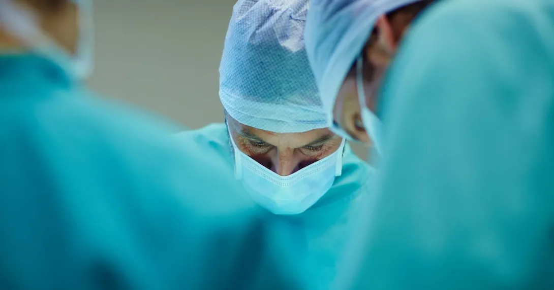 Three healthcare professionals performing surgery