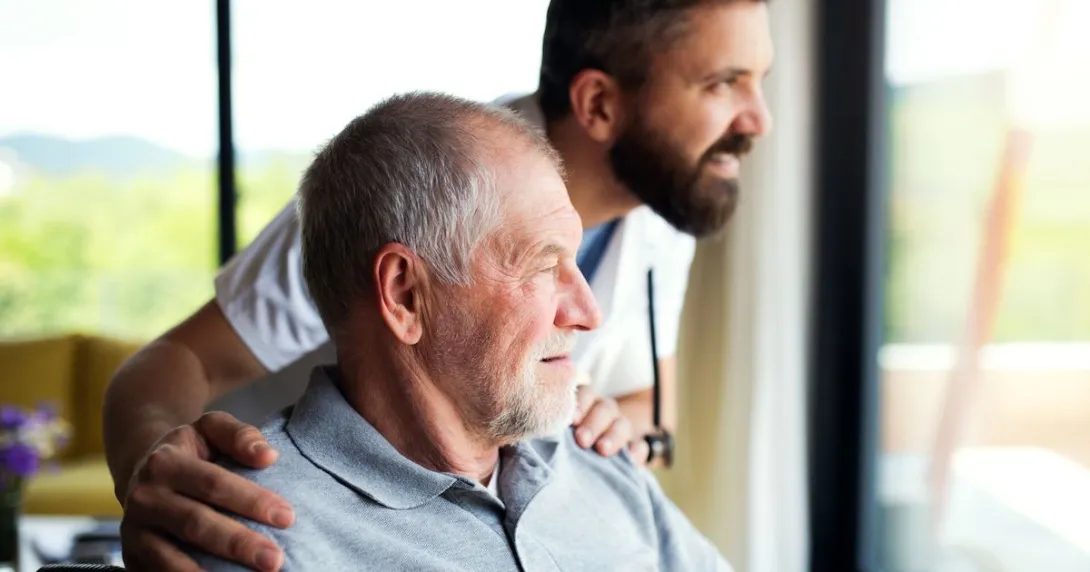 A senior patient and a caregiver looking out the window