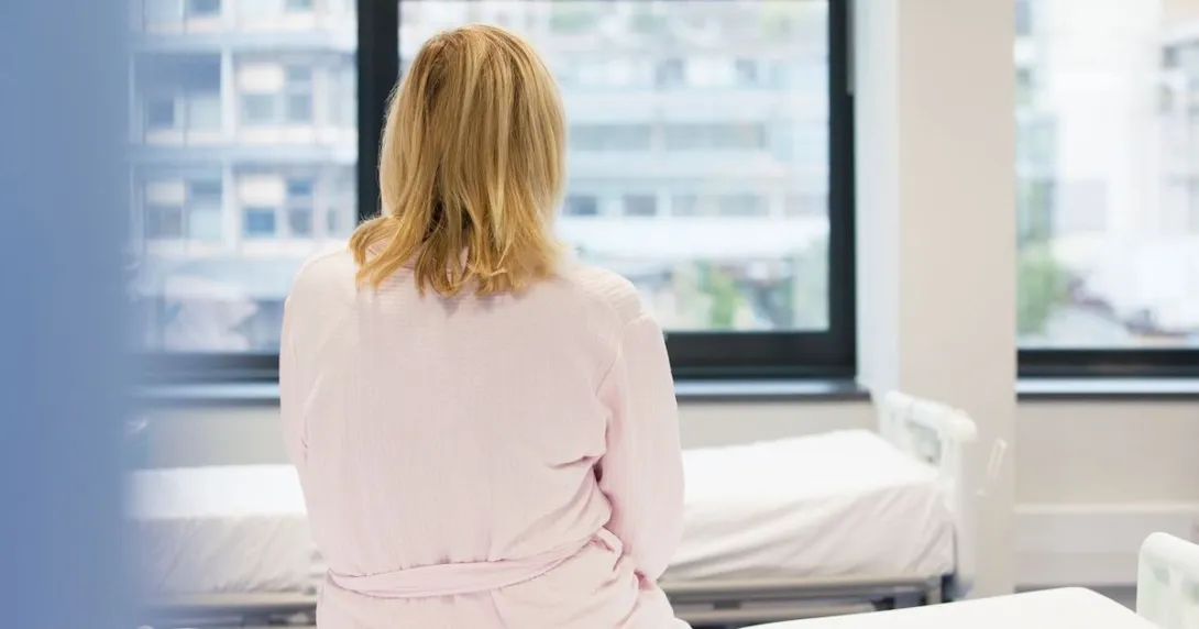 A photo of a woman sitting on a hospital bed